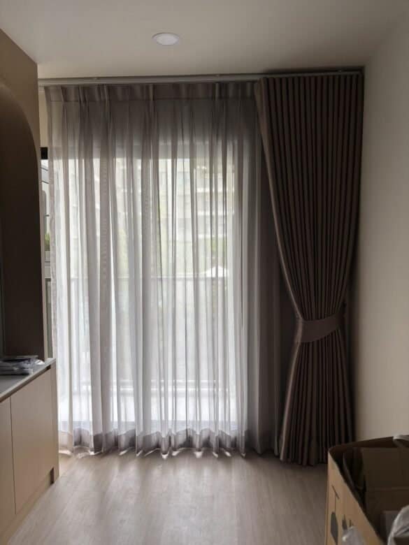Brown drape and sheer with a tieback on a tall window