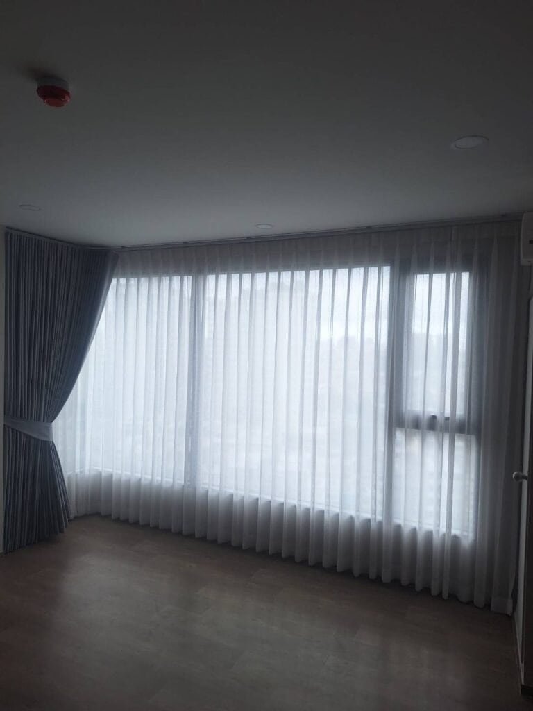 Sheer curtains on a corner window with a tieback, installed by NTS Curtain